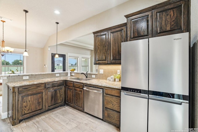 kitchen featuring stainless steel appliances, light stone countertops, sink, and kitchen peninsula