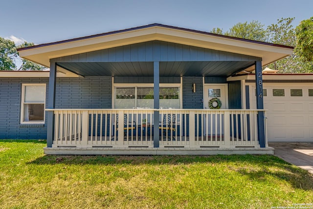 rear view of house featuring a porch, a garage, and a yard