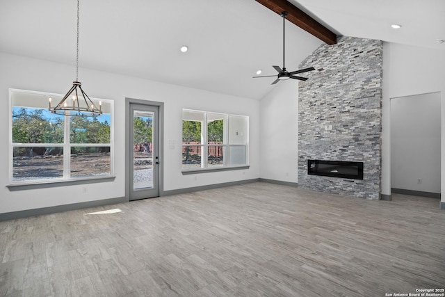 unfurnished living room featuring beam ceiling, wood-type flooring, high vaulted ceiling, a fireplace, and ceiling fan with notable chandelier