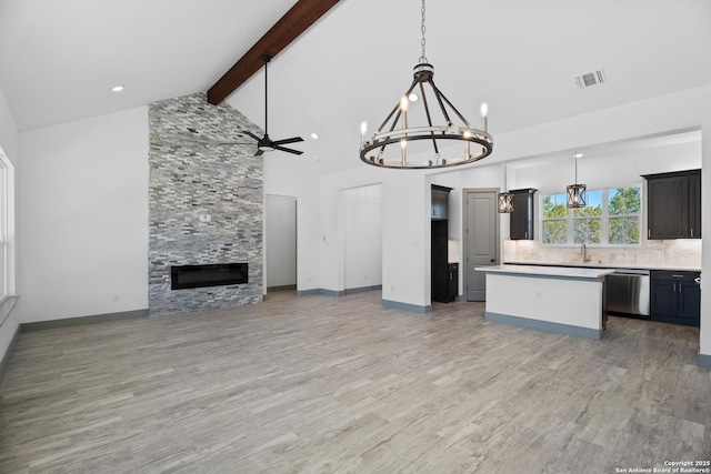 kitchen featuring dishwasher, hanging light fixtures, a fireplace, a kitchen island, and beamed ceiling