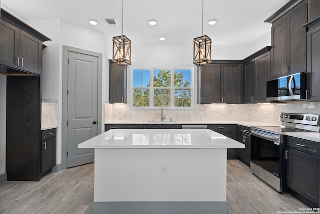 kitchen with dark brown cabinetry, sink, decorative light fixtures, a center island, and appliances with stainless steel finishes