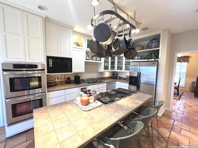 kitchen featuring tile countertops, black appliances, and white cabinets