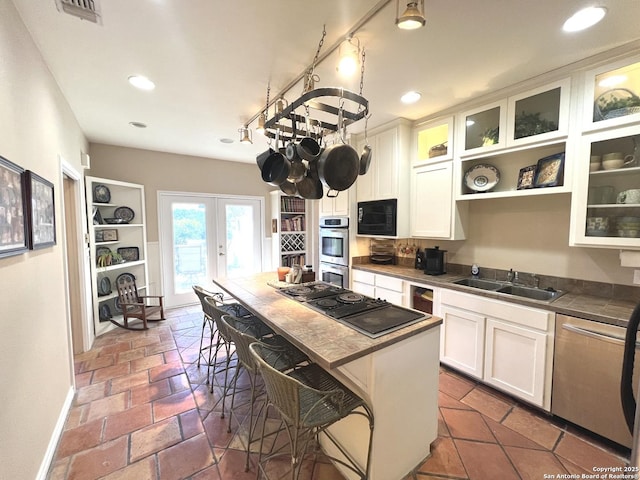 kitchen with sink, white cabinets, a kitchen breakfast bar, black appliances, and french doors