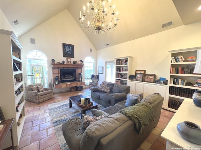 living room featuring a tiled fireplace, high vaulted ceiling, and an inviting chandelier