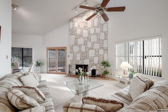 living room with high vaulted ceiling, carpet floors, track lighting, and a fireplace