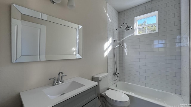 full bathroom featuring tiled shower / bath combo, vanity, and toilet