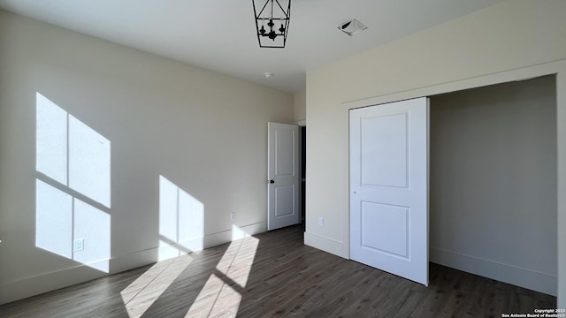 unfurnished bedroom with dark hardwood / wood-style floors and a closet