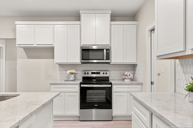 kitchen featuring stainless steel appliances, backsplash, white cabinets, and light stone counters