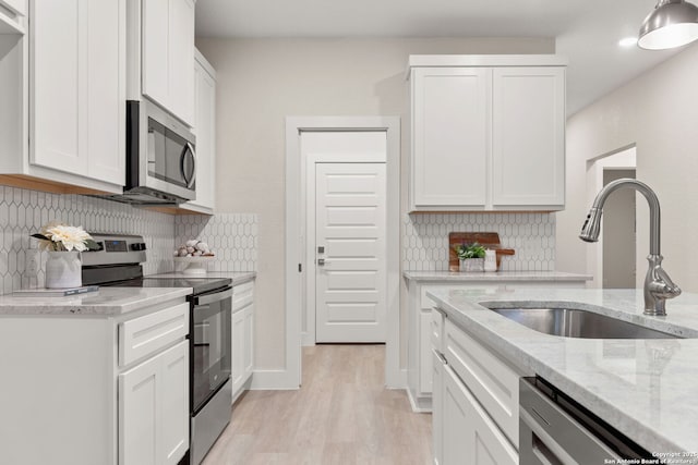 kitchen featuring sink, stainless steel appliances, light stone countertops, white cabinets, and decorative backsplash