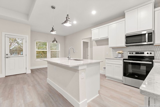 kitchen with sink, light stone counters, hanging light fixtures, stainless steel appliances, and white cabinets