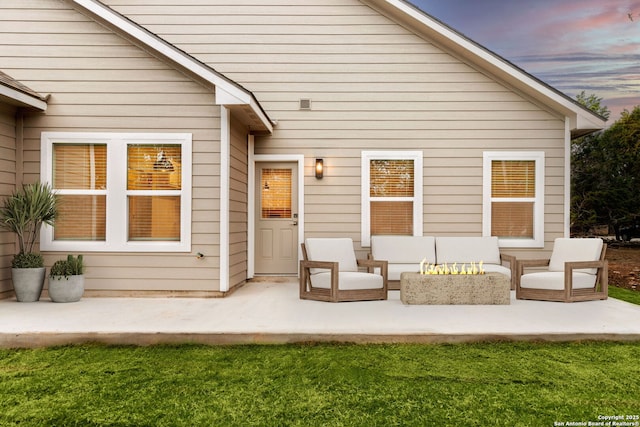 back house at dusk with a yard, a patio, and an outdoor living space with a fire pit