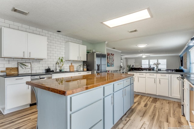 kitchen with white cabinetry, light hardwood / wood-style flooring, stainless steel appliances, and a center island