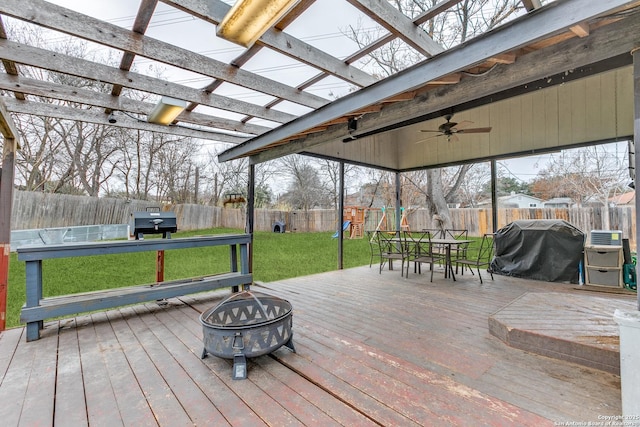 wooden deck featuring a playground, an outdoor fire pit, a yard, ceiling fan, and grilling area