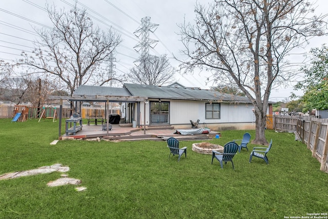 rear view of property with a playground, a yard, and a deck