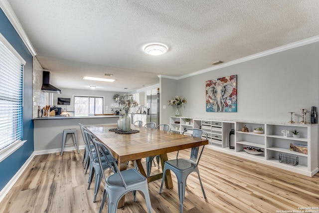 dining space with crown molding, a textured ceiling, and light hardwood / wood-style flooring