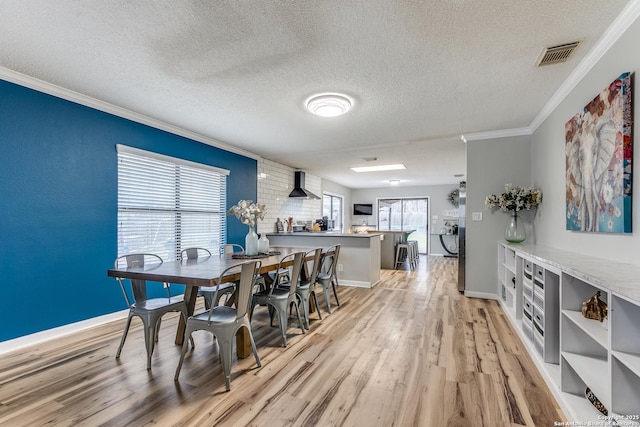 dining area featuring ornamental molding, a textured ceiling, and light wood-type flooring