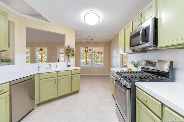 kitchen with light tile patterned flooring, sink, hanging light fixtures, green cabinets, and stainless steel appliances