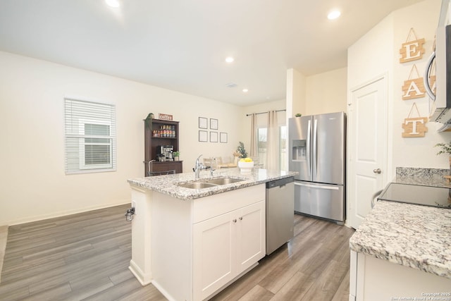 kitchen featuring appliances with stainless steel finishes, sink, white cabinets, hardwood / wood-style flooring, and a center island with sink