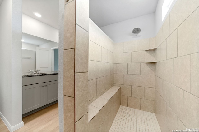 bathroom with tiled shower, wood-type flooring, and vanity