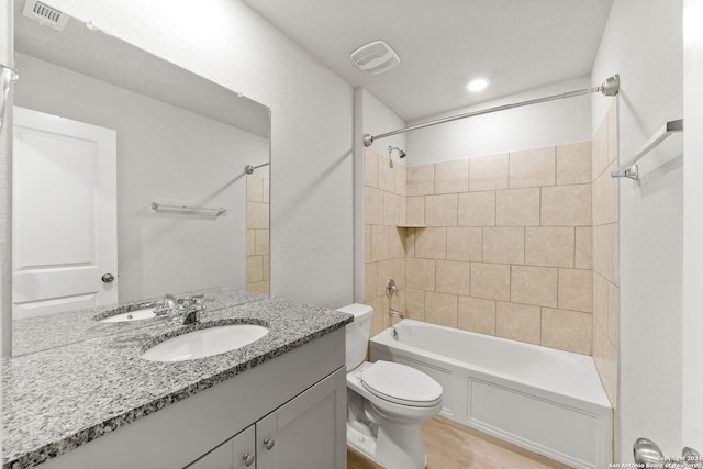 full bathroom featuring vanity, tiled shower / bath combo, and toilet