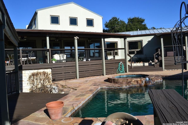 rear view of property with a swimming pool with hot tub and a patio area