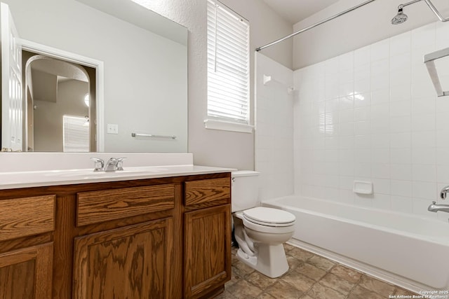 full bathroom featuring vanity, tiled shower / bath, and toilet