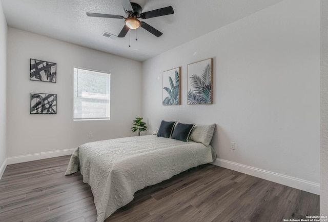 bedroom with dark wood-type flooring, ceiling fan, and a textured ceiling