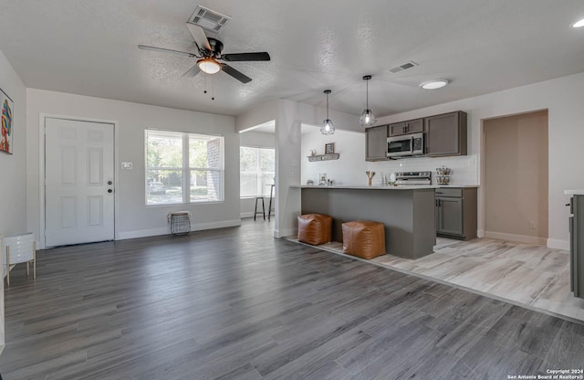 kitchen featuring hanging light fixtures, wood-type flooring, stainless steel appliances, and kitchen peninsula