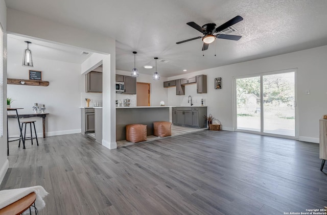 living room featuring a textured ceiling, ceiling fan, and light wood-type flooring