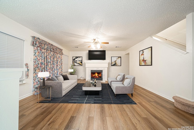 living room with a textured ceiling, wood-type flooring, and ceiling fan