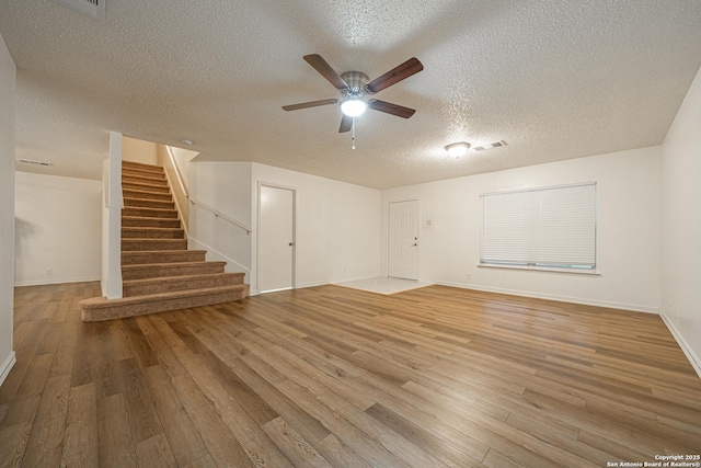 interior space featuring ceiling fan, wood-type flooring, and a textured ceiling