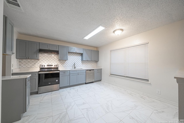 kitchen featuring sink, gray cabinets, appliances with stainless steel finishes, a textured ceiling, and decorative backsplash