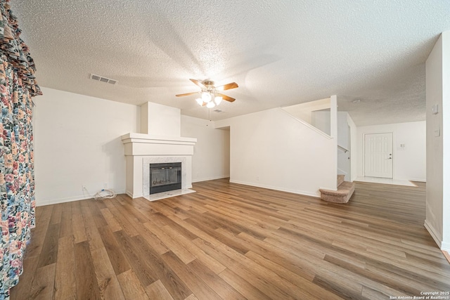 unfurnished living room featuring hardwood / wood-style flooring, ceiling fan, and a fireplace