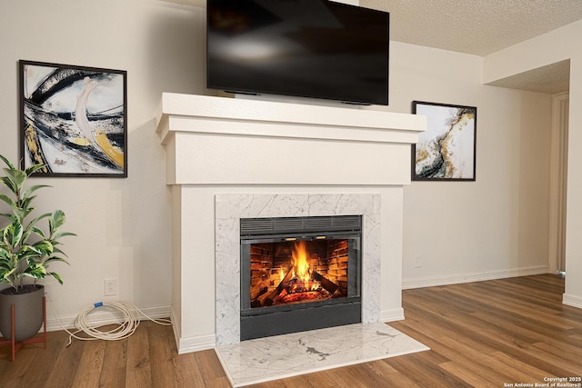 interior details with hardwood / wood-style flooring, a high end fireplace, and a textured ceiling