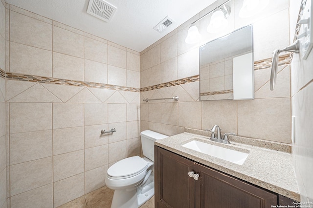 bathroom featuring tile walls, vanity, tile patterned flooring, and toilet