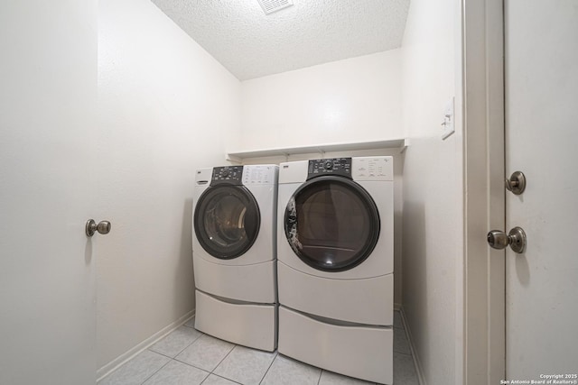 laundry area featuring separate washer and dryer, a textured ceiling, and light tile patterned flooring