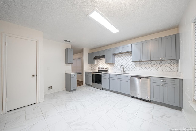 kitchen featuring sink, appliances with stainless steel finishes, gray cabinetry, backsplash, and a textured ceiling