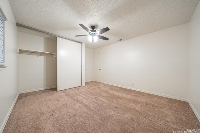 unfurnished bedroom with ceiling fan, carpet flooring, a closet, and a textured ceiling