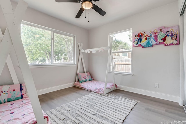 bedroom featuring ceiling fan, wood-type flooring, and multiple windows