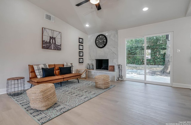 living room featuring hardwood / wood-style flooring, ceiling fan, a high end fireplace, and vaulted ceiling