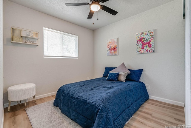 bedroom featuring ceiling fan, hardwood / wood-style floors, and a textured ceiling