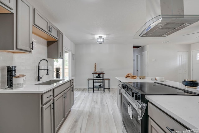 kitchen with sink, gray cabinetry, tasteful backsplash, light wood-type flooring, and electric stove