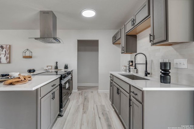 kitchen featuring gray cabinets, island range hood, tasteful backsplash, sink, and stainless steel range with electric cooktop