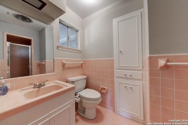 bathroom with vanity, toilet, tile patterned flooring, and tile walls