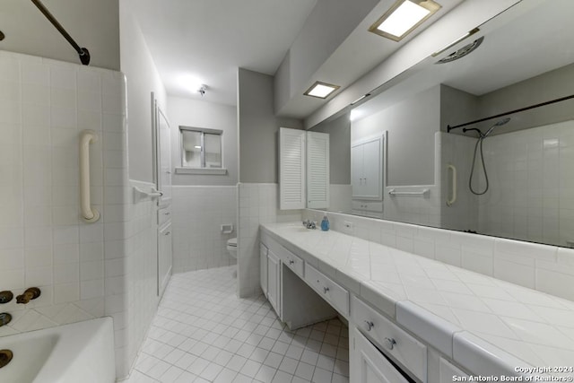 full bathroom featuring tile patterned flooring, tile walls, tiled shower / bath combo, vanity, and toilet