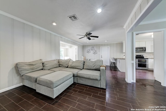 living room featuring dark wood-type flooring, ornamental molding, and ceiling fan