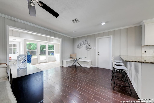 interior space with ornamental molding, dark wood-type flooring, ceiling fan, and french doors