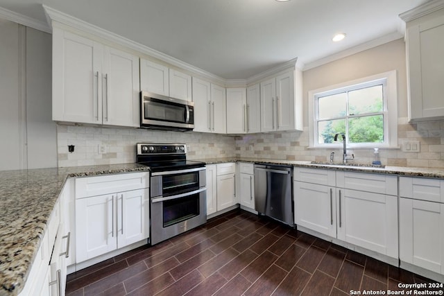 kitchen featuring sink, appliances with stainless steel finishes, light stone counters, tasteful backsplash, and white cabinets