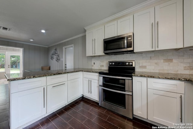 kitchen with white cabinetry, dark stone countertops, ornamental molding, kitchen peninsula, and stainless steel appliances