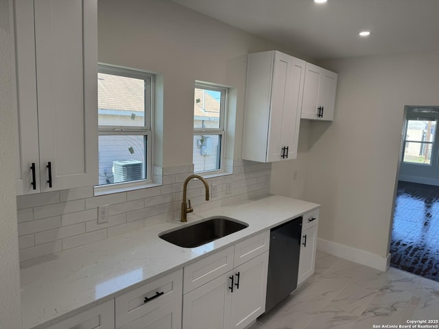 kitchen featuring sink, dishwasher, white cabinetry, tasteful backsplash, and light stone countertops